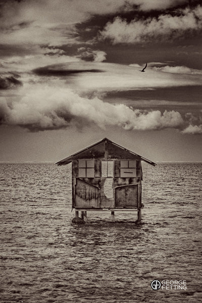Slightly surreal view of the remnants of a fisherman's hut sits over the water