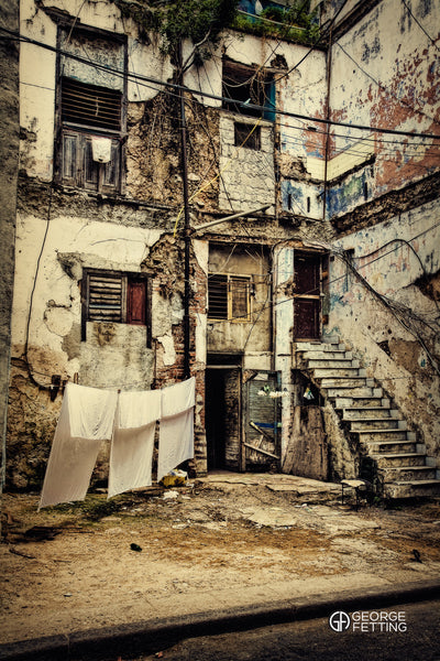 three white sheets hanging to dry outside derelict building