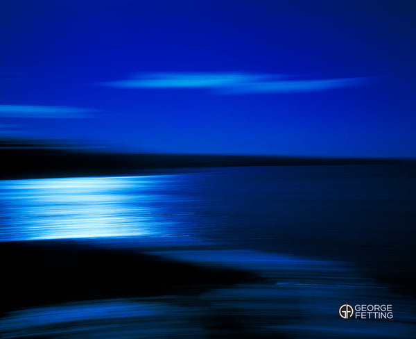 A lightening bolt cloud sits above a shimmering Pacific Ocean
